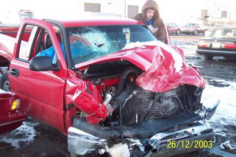 1990 Ford Taurus - A red pickup truck sustained heavy damage to its front end and windshield after an accident.