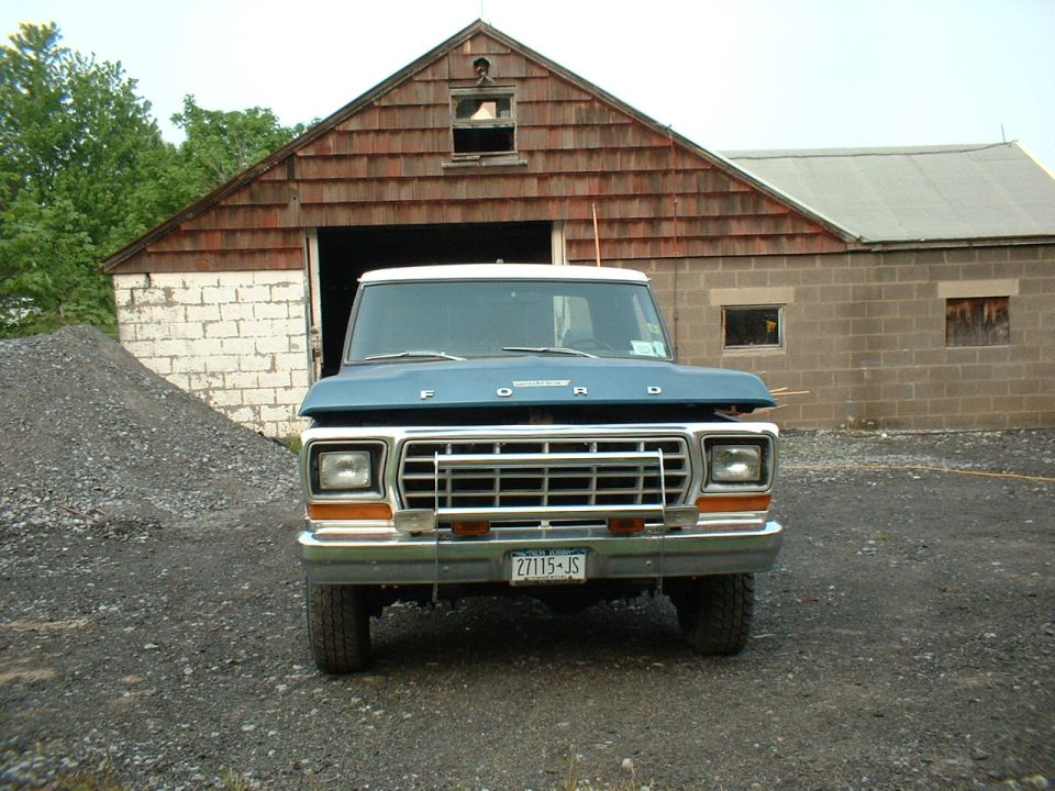Blue 1978 Ford F-250 front view with hood open, parked in front of a barn