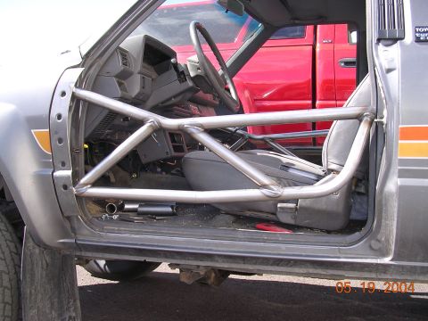 1994 Ford Bronco - The interior of a gray Toyota truck is visible, a roll cage and a red truck in the background. The photo is dated 05.19.2004.