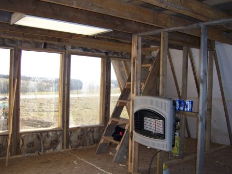 1999 Jeep TJ - The interior of a room shows unfinished construction with exposed wood, insulation, and a wall-mounted heater.
