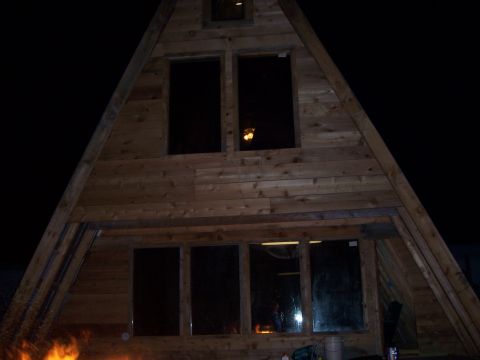 1999 Jeep TJ - Exterior view of a wooden A-frame structure at night, illuminated by a fire.