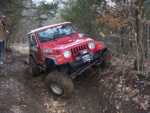 1999 Jeep TJ - Red 1999 Jeep TJ navigates a challenging muddy off-road trail.
