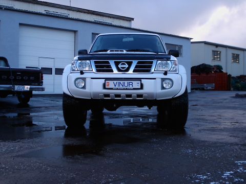 1996 Ford Bronco - Front view of a white Nissan Patrol SUV with a Dodge pickup truck visible on the left.