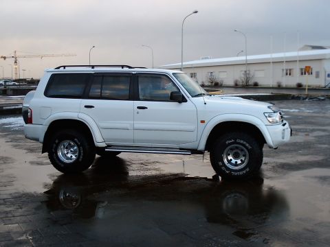 1996 Ford Bronco - A white SUV is parked on a wet, reflective surface under an overcast sky.