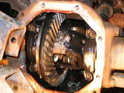 1986 Ford F-150 - Close-up view of the differential gears, coated in dark grease, with the Supermotors.net logo in the corner.