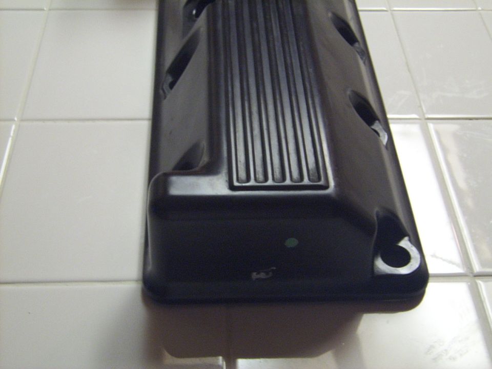Black valve cover with ribbed detail and mounting holes