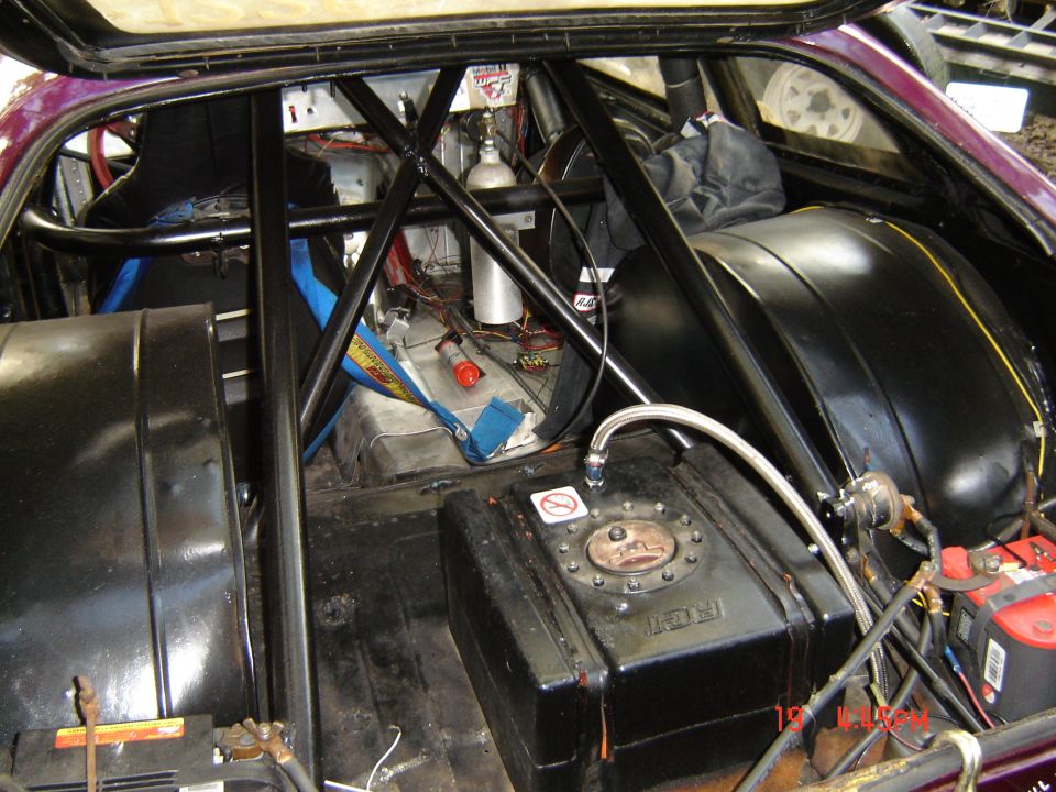 Gutted race car interior with roll cage, black RCI fuel cell, nitrous bottle and battery
