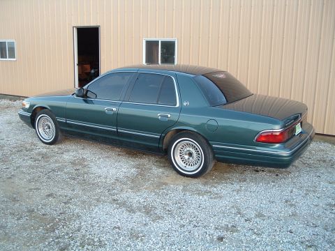 1995 Mercury Grand Marquis - A 1995 Mercury Grand Marquis is parked on a gravel lot in front of a metal building.