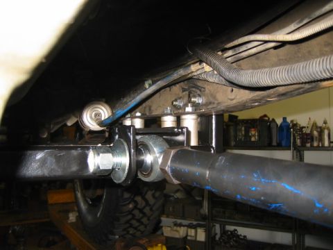 1992 Ford Bronco - Underside view of a vehicle's suspension and steering components, showing a large silver bolt and nut joining a heavy metal arm with blue p…