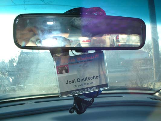 Car show lanyard badge hanging from a windshield rear-view mirror inside a car