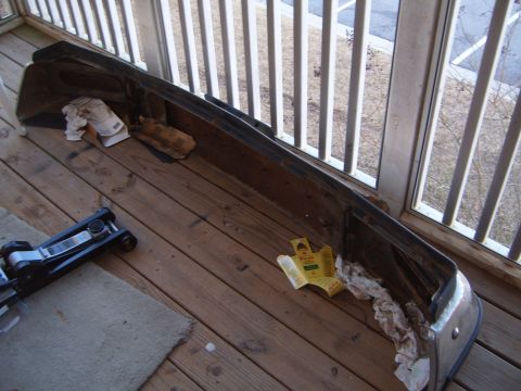 1988 Ford Bronco - A detached vehicle bumper rests on a wooden deck, with a car jack nearby.
