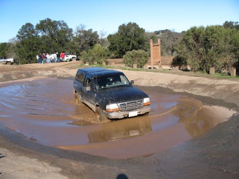 1998 Ford Ranger - A black 1998 Ford Ranger navigates a muddy obstacle course with onlookers in the background.
