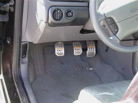 1995 Ford Contour - Aftermarket MOMO pedals installed in a car's interior, with visible steering wheel and dashboard.