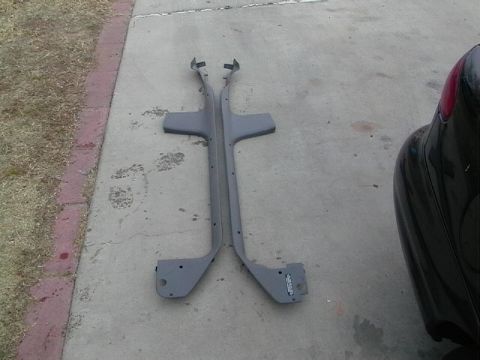 1995 Ford Contour - Two gray plastic door sill plates are laid out on a concrete surface next to a black vehicle.