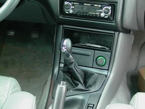 1995 Ford Contour - Close-up of a car's center console a gear shifter and an aftermarket stereo system.