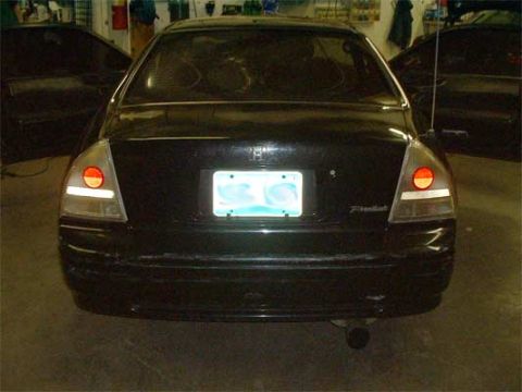 1993 Ford Probe - A black sedan is viewed from the rear with its doors open, showing a license plate and a watermark.