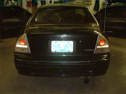 Black sedan rear view with doors open, license plate obscured, and Supermotors watermark