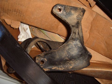 1988 Ford Bronco - A dirty metal bracket is shown inside a cardboard box, with some fabric and other parts visible.