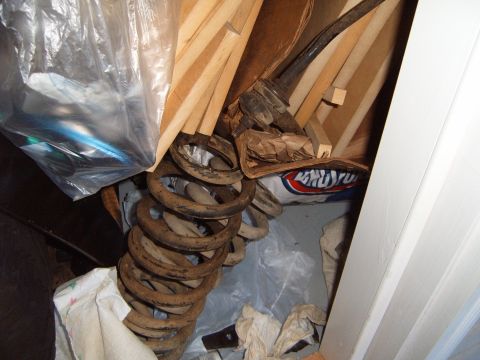 1988 Ford Bronco - Suspension springs and wooden planks are stored together, obscuring any potential vehicle identification.