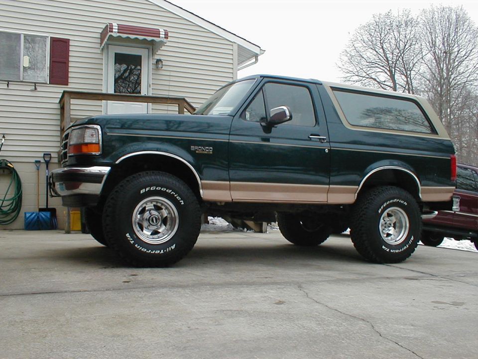 Dark green 1990s Ford Bronco with Eddie Bauer trim and lift parked in a driveway
