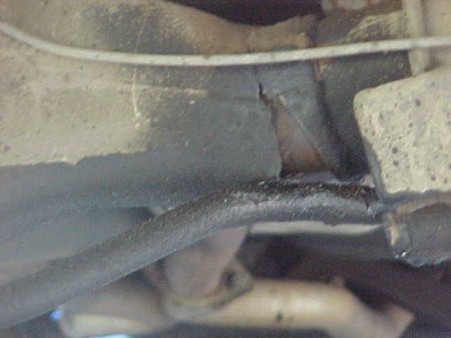 Underside view of vehicle frame rail and exhaust pipe with surface rust