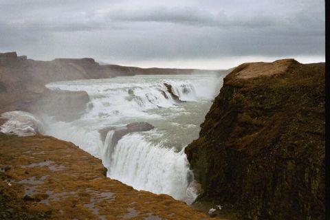 1993 Ford Bronco - A powerful waterfall flows over terrain, with a dramatic cloudy sky overhead.