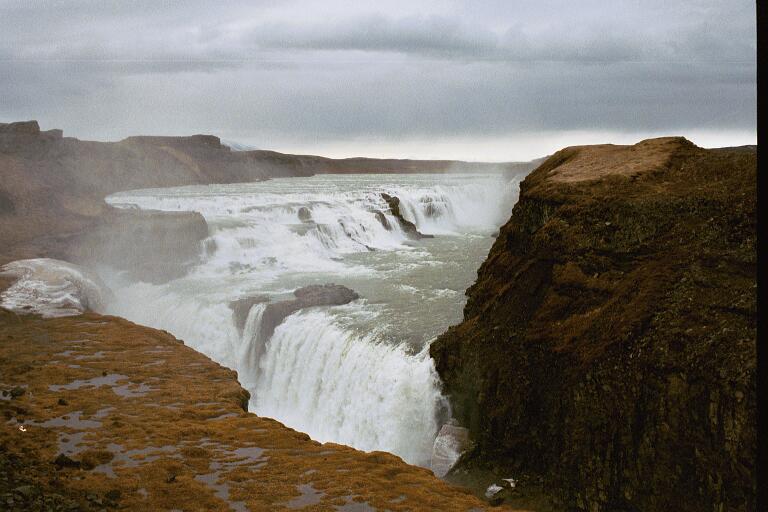 Waterfall cascading over rocky cliffs under a cloudy sky