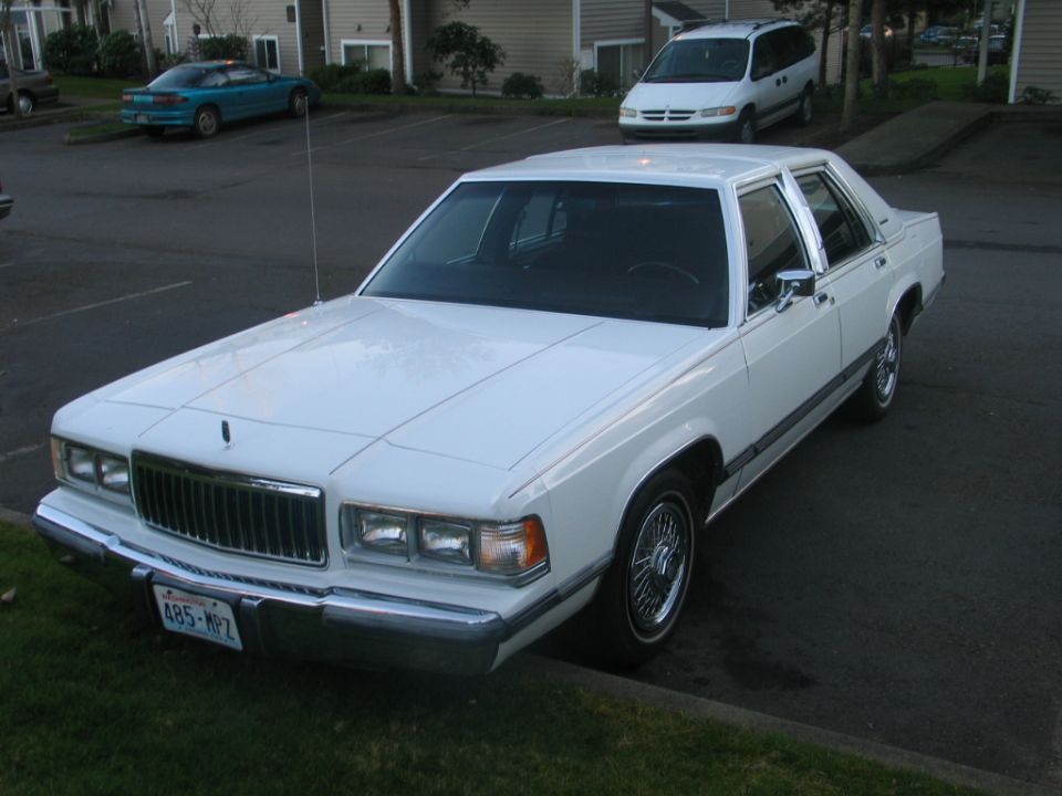 White Mercury Grand Marquis sedan with wire wheels and Washington plate 485-MPZ in a parking lot