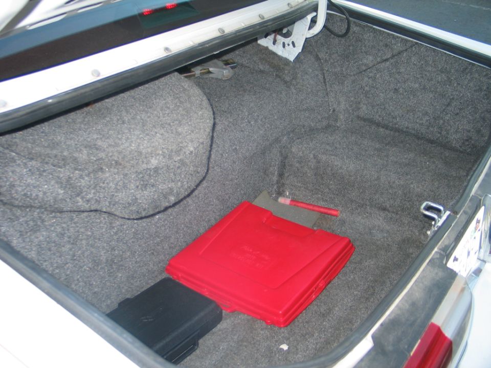 Trunk interior with spare tire well, red tool case, and black box
