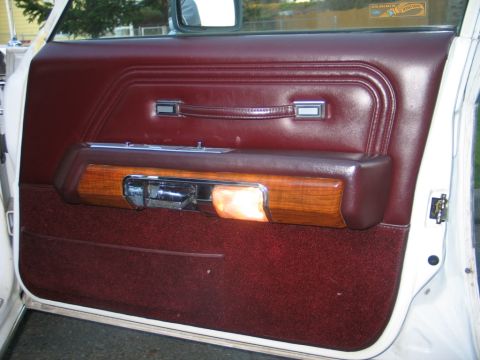 1988 Mercury Grand Marquis - Close-up of a car's interior door panel, maroon upholstery and wood grain accents.