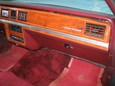 1988 Mercury Grand Marquis - The interior of a 1988 Mercury Grand Marquis shows woodgrain trim on the dashboard and red carpeting.