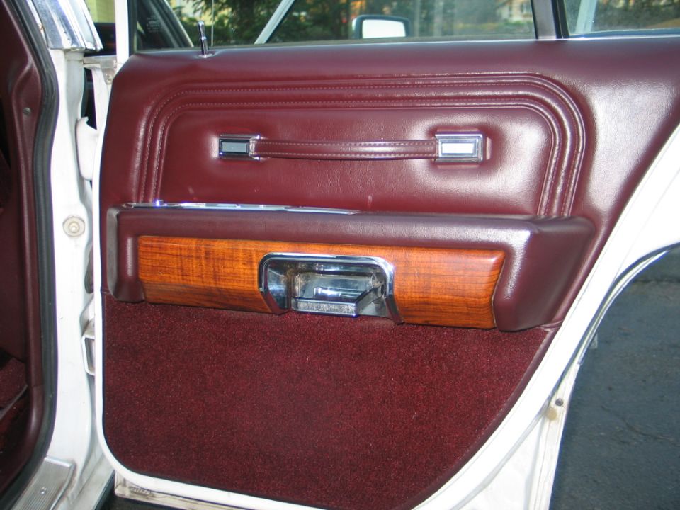 Maroon interior door panel with wood trim and chrome handle