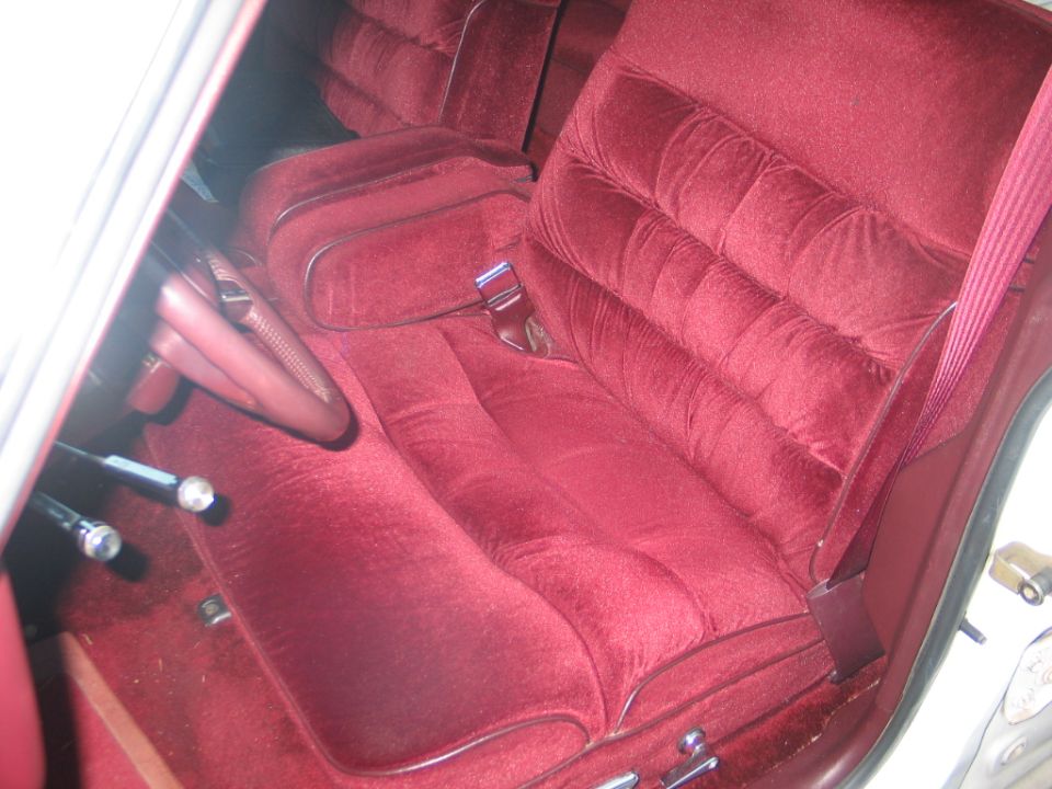 Red velour car interior with tufted seats and a steering wheel visible
