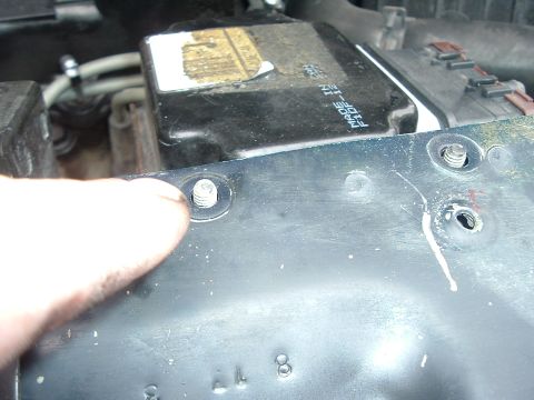 1993 Ford Taurus - Close-up view of a part in the engine bay, showing some text and a screw being held by a finger.