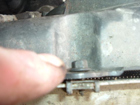 1993 Ford Taurus - Close-up of a vehicle radiator component with a finger indicating a mounting point.