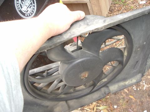 1993 Ford Taurus - A person holds a radiator fan shroud, revealing the fan blades within the part.