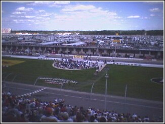 1993 Ford Bronco - A wide view of a racetrack during an event, with many cars parked in the background and spectators in the stands.