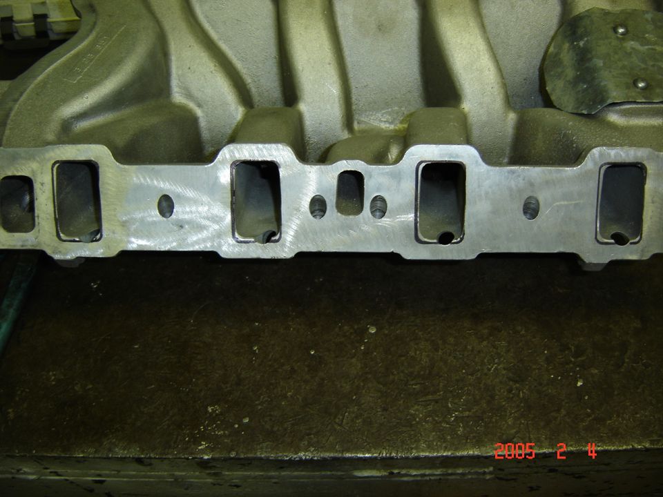 Machined port face of an aluminum V8 intake manifold on a workbench