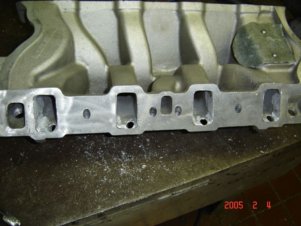 Aluminum intake manifold flange with port-matched rectangular runners on a workbench