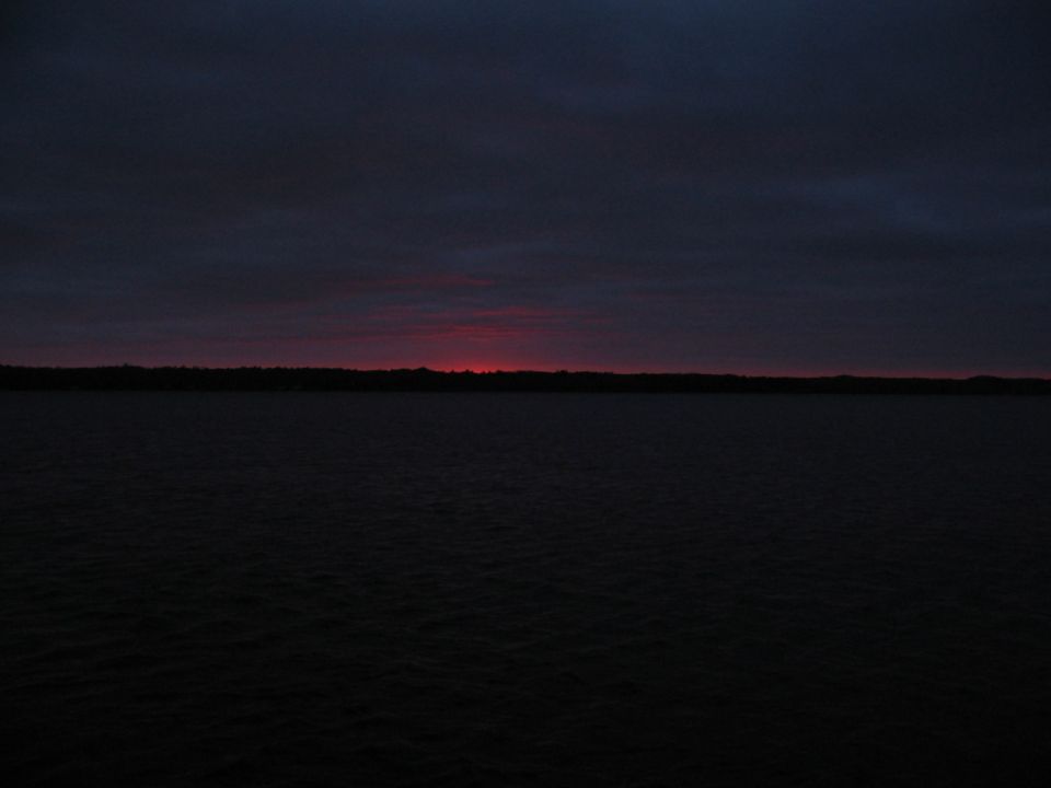 Dusk sky with a faint red horizon band over a dark lake