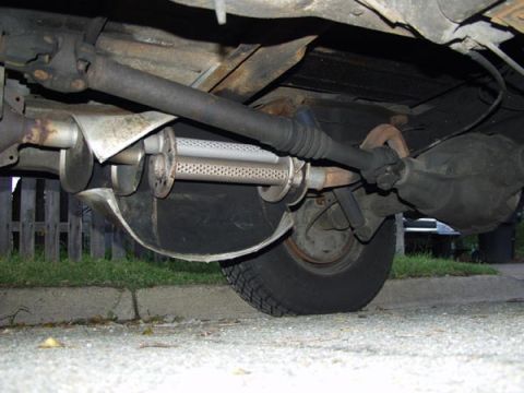 1988 Ford Bronco - The underside of a vehicle reveals its exhaust system and rear axle components.