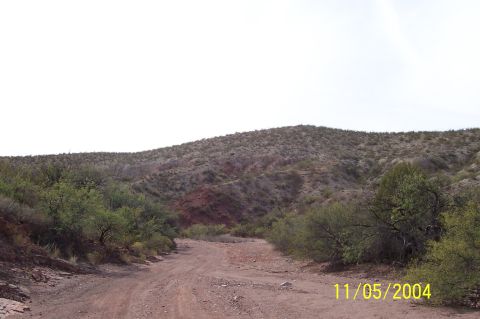 1994 Ford Bronco - A dirt road leads through a sparsely vegetated desert landscape with rolling hills under a clear sky.