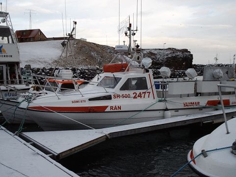 1996 Ford Bronco - Multiple boats are docked in a harbor during winter, with snow on the ground and surrounding hills.