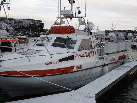 1996 Ford Bronco - A white fishing boat with a red stripe is docked in a harbor, with other boats visible in the background.