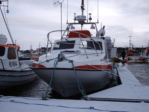 1996 Ford Bronco - A white and orange boat is tied to a dock in a harbor covered in snow.