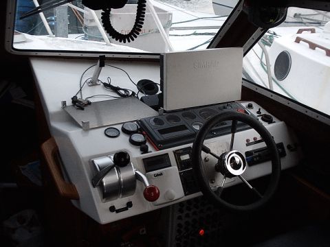 1996 Ford Bronco - The interior of a boat's helm features a Simrad navigation display, steering wheel, and various control levers.