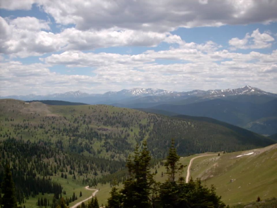 Mountain landscape with winding road and trees under cloudy sky