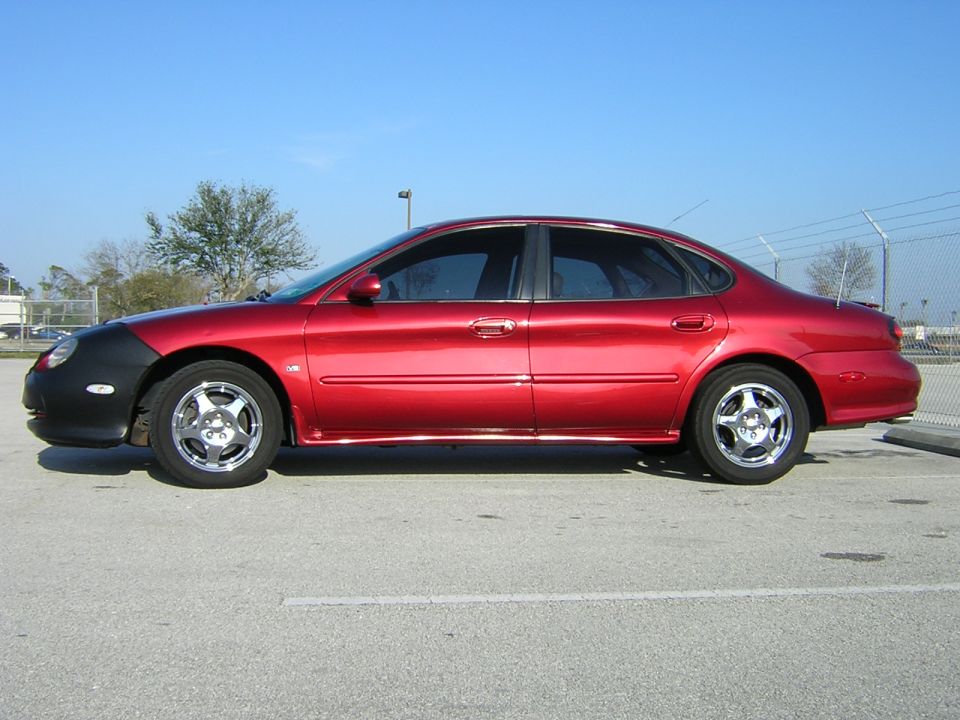 Red sedan with a black car bra, side view. Appears to be a 2000 model year