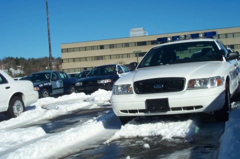 2001 Ford Crown Victoria - Multiple police vehicles, including a white 2001 Ford Crown Victoria, are parked in a snowy lot.