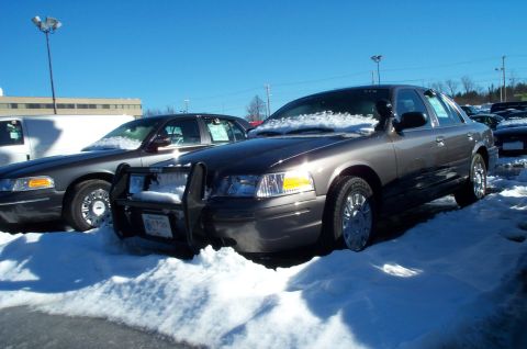 2001 Ford Crown Victoria - Two Ford Crown Victorias are parked in the snow, one with a push bumper.